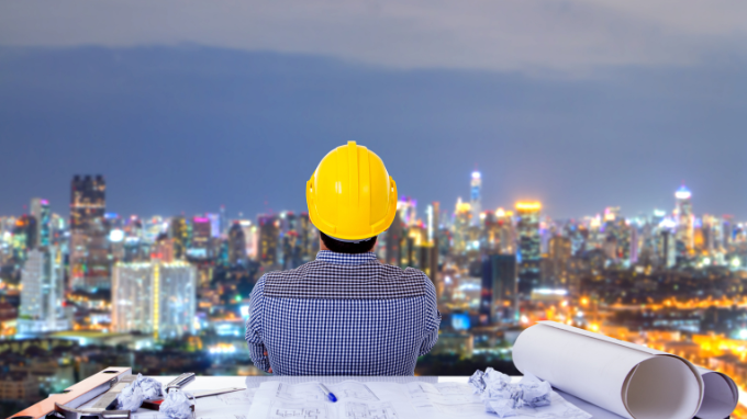 Construction worker at his desk looking out on the city horizon.