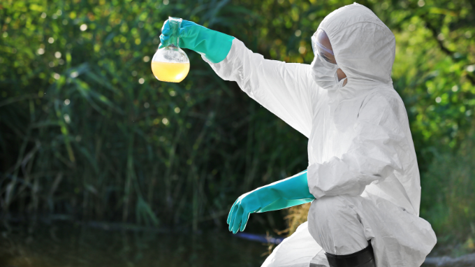 Environmental scientist holding and examining water sample.