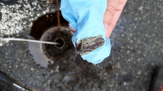 A hand holding a contaminated water sample.